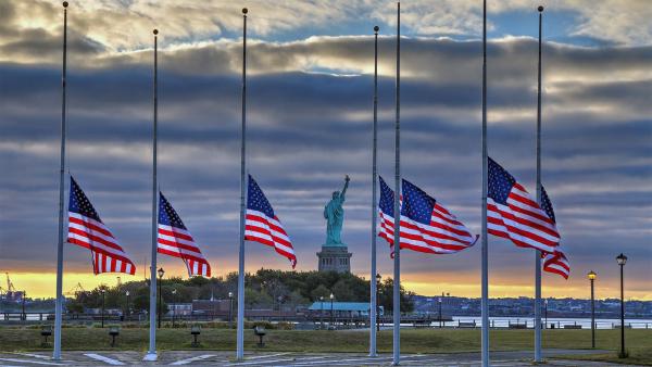 Statue of Liberty seen behind US flags at half-staff for the anniversary of